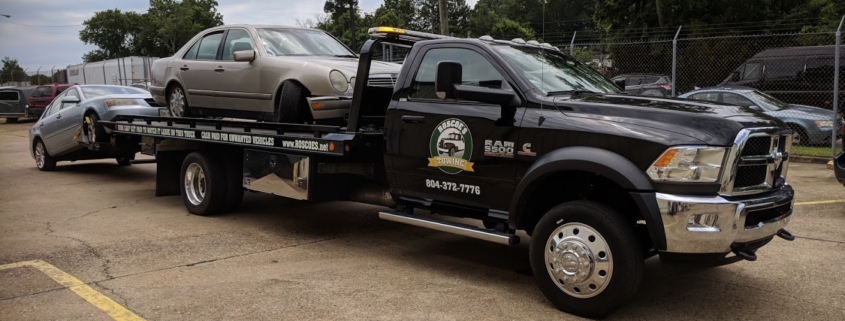 roscoes junk cars rollback with logo on door loaded with two vehicles